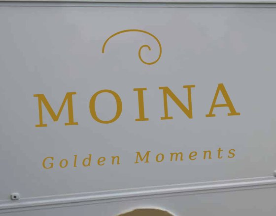 Der goldene MOINA-Schriftzug auf dem Anhänger aus der Nähe